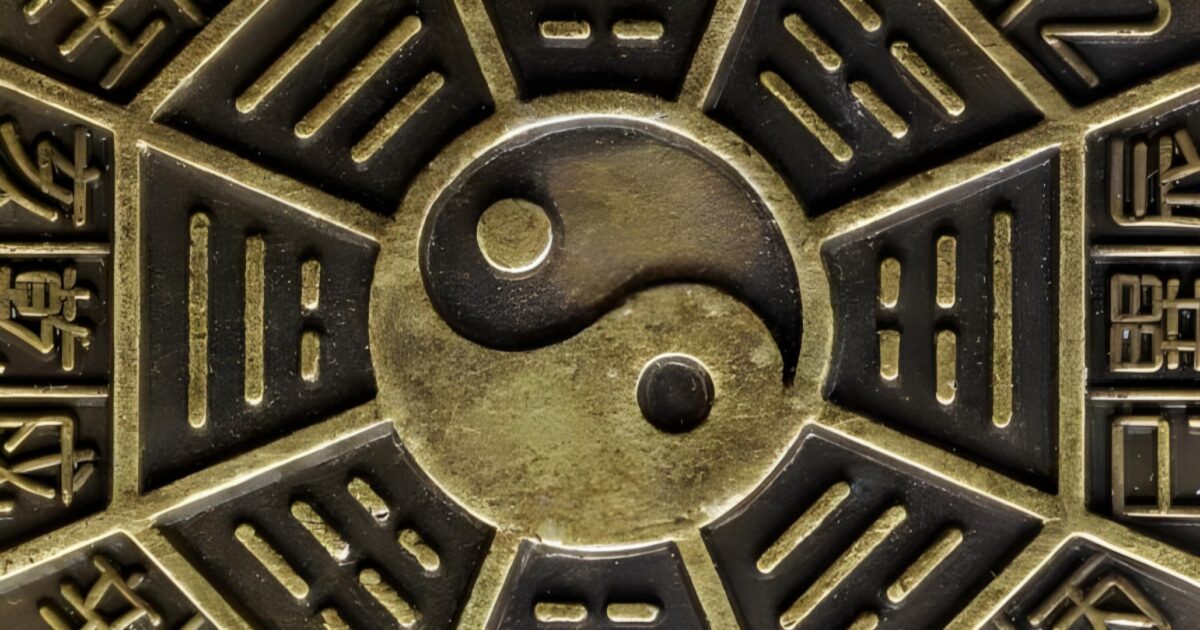 The image shows a close-up of a surface with a Yin-Yang symbol at the center, surrounded by intricate patterns and Chinese characters. The Yin-Yang is depicted in classic black and white contrasting colors, symbolizing dualism or balance in Chinese philosophy. The surrounding patterns are geometric and symmetrical, with the Chinese characters possibly conveying specific meanings or sayings related to the philosophy of balance.