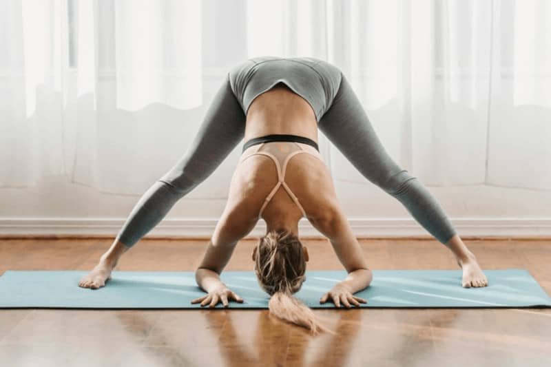 In Wide Legged Forward Fold Pose, you can grab onto the ankles, toes, or bend your elbows to place your forearms on the floor.